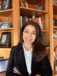 Zahra Emam pictured in a black blazer in front of a bookshelf