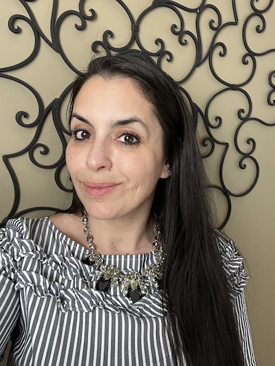 Zahra Murphy pictured in front of metal wall decor in a black and white blouse